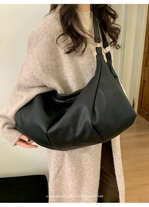 Detail of black lychee texture leather tote with silver metal ring on the shoulder strap