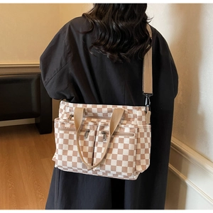 Detail of checkered canvas crossbody bag with multiple front zipper pockets and wide strap