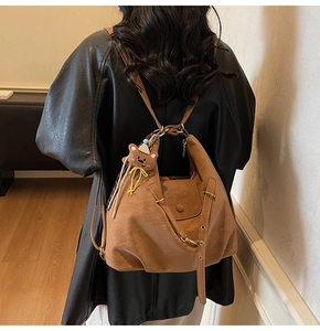 Detail of vintage brown leather tote bag with a cute plush bear charm on the strap