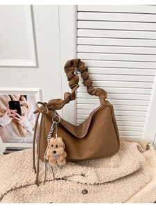 Detail of dark brown tote bag featuring a scrunchie strap and plush bear charm
