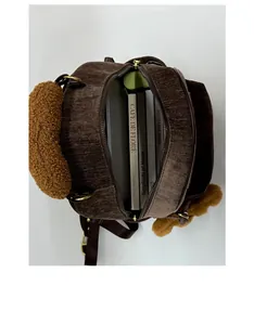 Spacious interior of a brown corduroy backpack with books and gold metal zipper detail