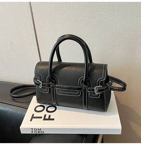 Detail der schwarzen Bowlingtasche aus genarbtem Leder mit weißen Kontrastnähten und Silberbeschlägen