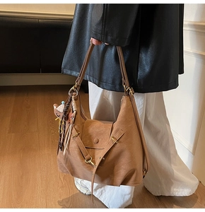 Close-up of caramel brown leather tote bag with a small bear pendant and vintage gold hardware