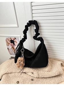 Close-up of black pleated hobo bag with cloud-like handle and cute brown teddy bear charm