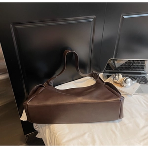 Vue macro d'un grand sac cabas en cuir mat marron foncé avec une large bandoulière réglable