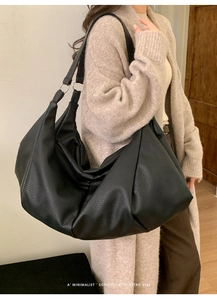 Detail view of the black wrinkled leather texture and silver buckle on the tote bag