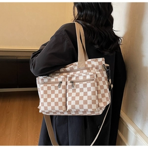 Detail of checkered canvas tote bag featuring double front zipper pockets and wide strap