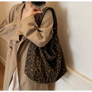 Detail view of large leopard print canvas hobo bag with wide shoulder strap on a model