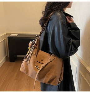 Detail of vintage brown tote bag with bear charm and tassel on a female model