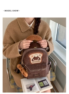 Detailed close-up of brown corduroy backpack with cute chef puppy patch and bread handle
