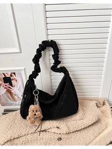 Detail of black crescent tote bag with a soft cloud handle and a plush bear charm accessory