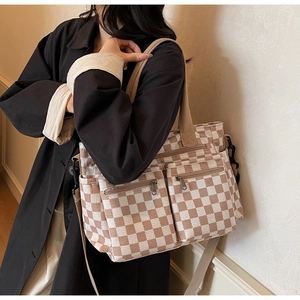Checkered canvas tote bag with multiple zipper pockets shown as a side crossbody style
