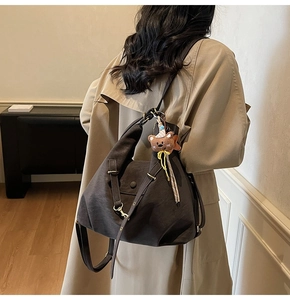Detailed side view of matte faux suede bucket bag with a cute plush bear charm