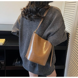 Side view of a vintage brown bucket shoulder bag worn by a model in a city setting