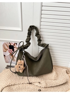 Detail of olive green leather tote featuring pleated handle and cute plush puppy charm