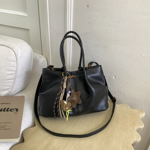 Vue détaillée du sac à main en cuir noir avec breloques d'étoile et d'ours et cordes tressées