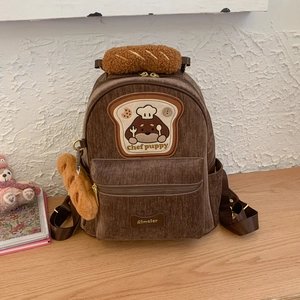 Detail of brown corduroy backpack with puppy chef embroidery and plush bread handle