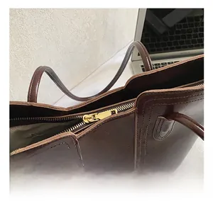 Detail of dark brown oil wax leather tote bag with premium gold metal zipper closure