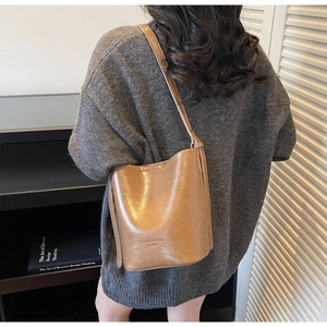 Detail view of camel leather bucket bag texture and fashion lettering on the side