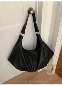 Detail of black pleated tote bag with lychee texture and silver metal ring hardware