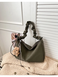 Detail of dark green tote bag featuring textured faux leather and a cute plush dog charm