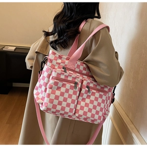 Rear view of a model wearing a pink checkered canvas tote bag with double front zip pockets