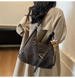 Detail view of coffee brown leather tote showing soft texture and bear keychain accessory