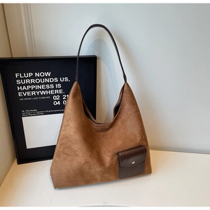 Dettaglio di una borsa tote in camoscio marrone con tasca in pelle e fibbia in metallo