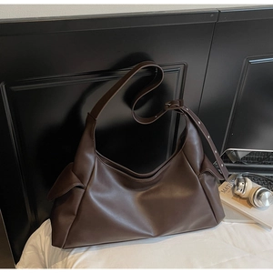 Détail d'un grand sac hobo en cuir mat marron foncé avec des poches latérales pour le bureau