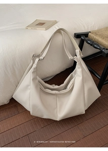 Detail of minimalist oversized cream tote bag showing pleated leather and silver hardware