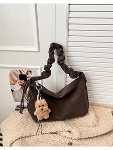 Detail of dark brown tote bag with ruffled handles and a cute plush dog pendant