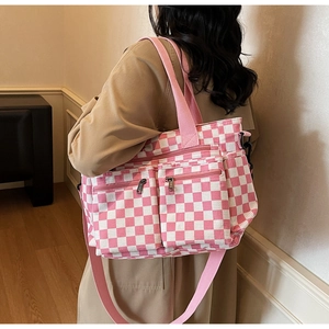 Pink and white checkered tote bag with dual front zipper pockets shown in use