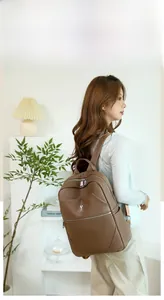 Detail of brown leather backpack featuring a cute rabbit logo and premium metal zipper