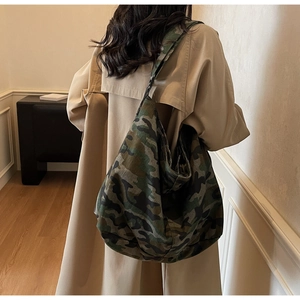 Close-up of camouflage canvas tote bag worn by a model showing large capacity and soft texture
