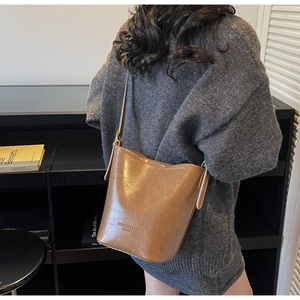 Close-up of brown vintage leather bucket bag with fashion logo and adjustable strap