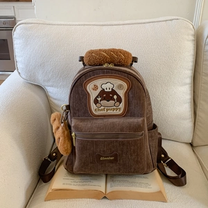 Detail of cute puppy embroidery and plush baguette-shaped handle on brown backpack