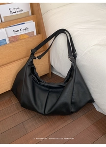 Macro shot of black pebbled leather tote bag with soft pleated design and silver ring