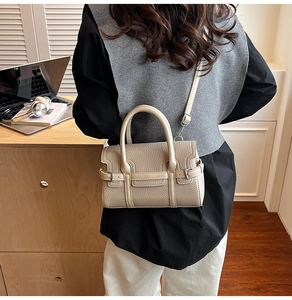 Beige Bowlingtasche aus Lederimitat neben einem Laptop in einer Büroumgebung gezeigt
