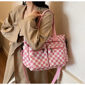 Detail of pink checkerboard canvas tote with functional front zippers and shoulder strap