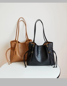 Detail of large tote bags in brown and black featuring an ostrich leather texture finish
