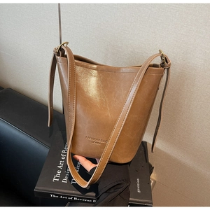 Close-up of brown leather bucket bag with metallic buckles and fashion logo on base