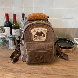 Detail of corduroy backpack featuring Chef Puppy embroidery and bakery theme decoration