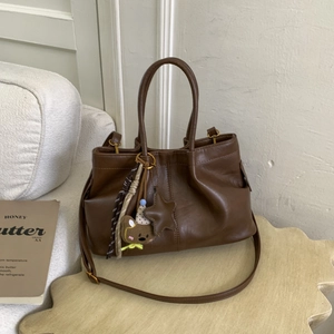 Gros plan du sac seau en cuir PU marron avec breloque ours en peluche et plis détaillés