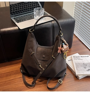 Close-up of vintage brown leather tote bag with a cute plush bear charm on a wooden floor