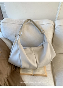Detailed texture of beige pleated hobo bag with wide strap on a minimal background