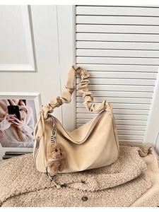 Close-up of beige faux leather tote bag with pleated handle and plush bear charm