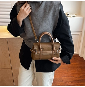 Close-up of deep brown litchi grain leather texture and stitching on women handbag