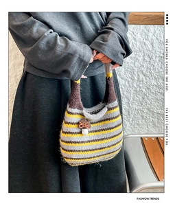 Detail of hand-crocheted striped tote bag with red mushroom charm and knit texture