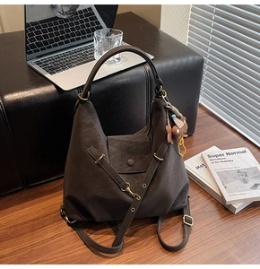 Detail of dark brown matte faux leather tote bag with vintage metal buckle and plush bear charm