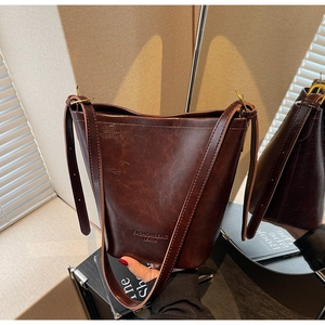 Detailed side view of dark brown retro bucket bag with wax texture and adjustable strap